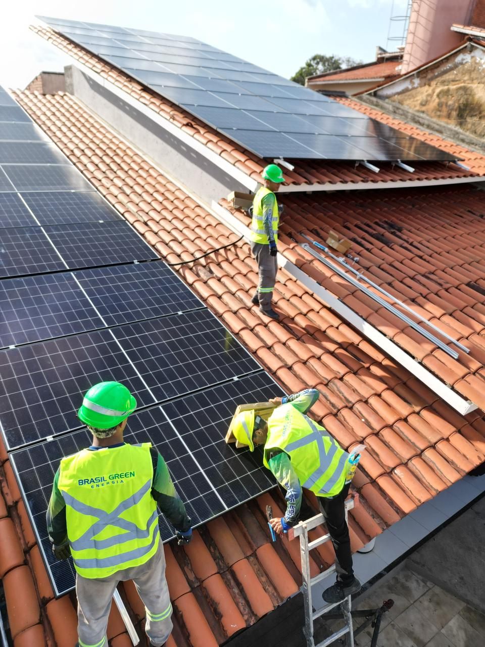Equipe da Brasil Green com colete e capacete instalando painéis em telhado cerâmico