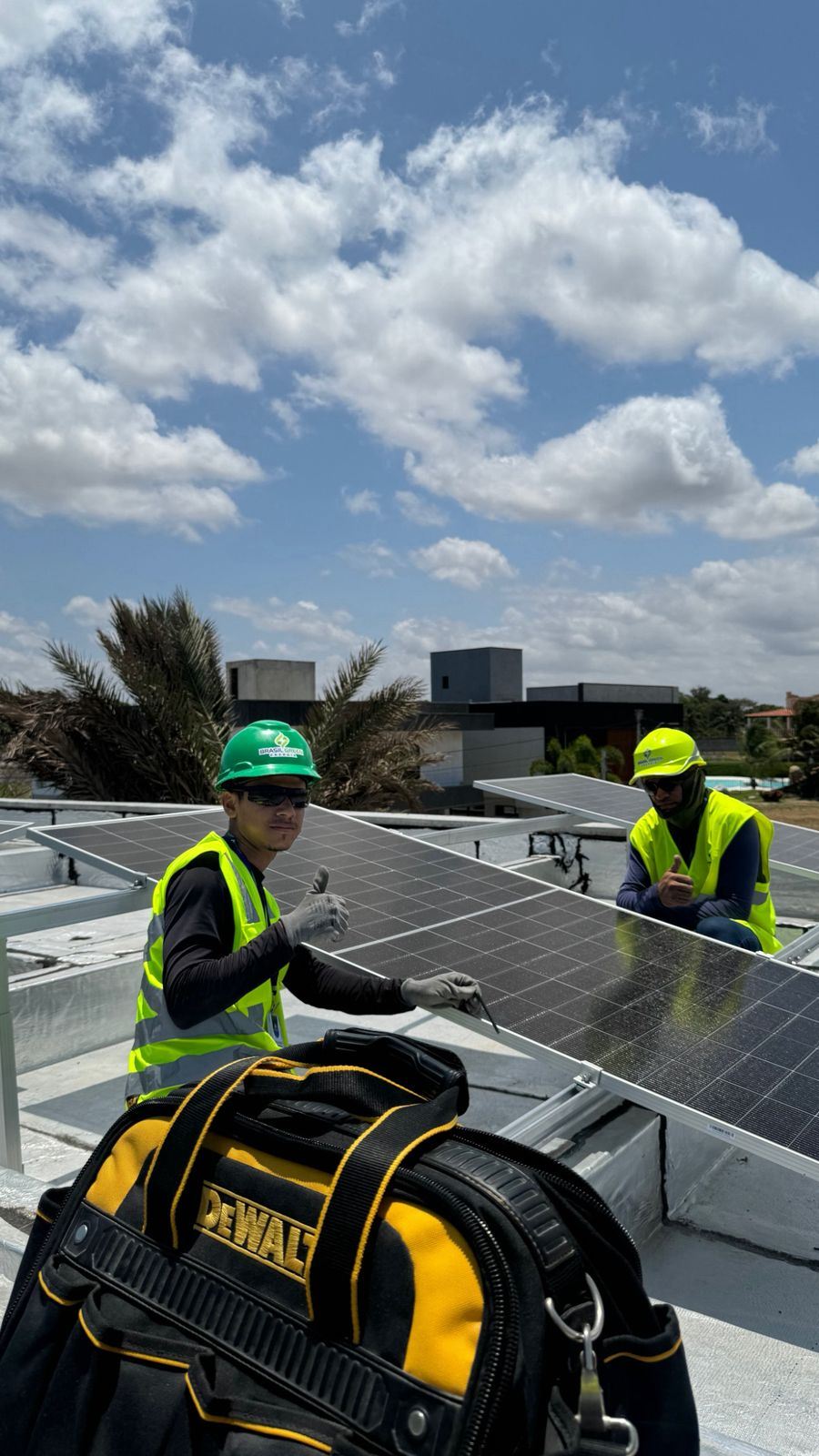 Dois instaladores da Brasil Green com capacete e colete entre painéis solares
