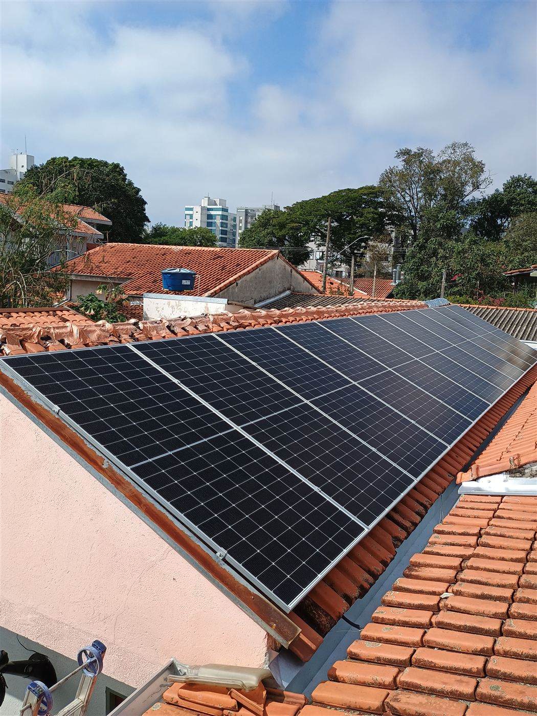 Sistema solar instalado em telhado residencial, com a cidade ao fundo